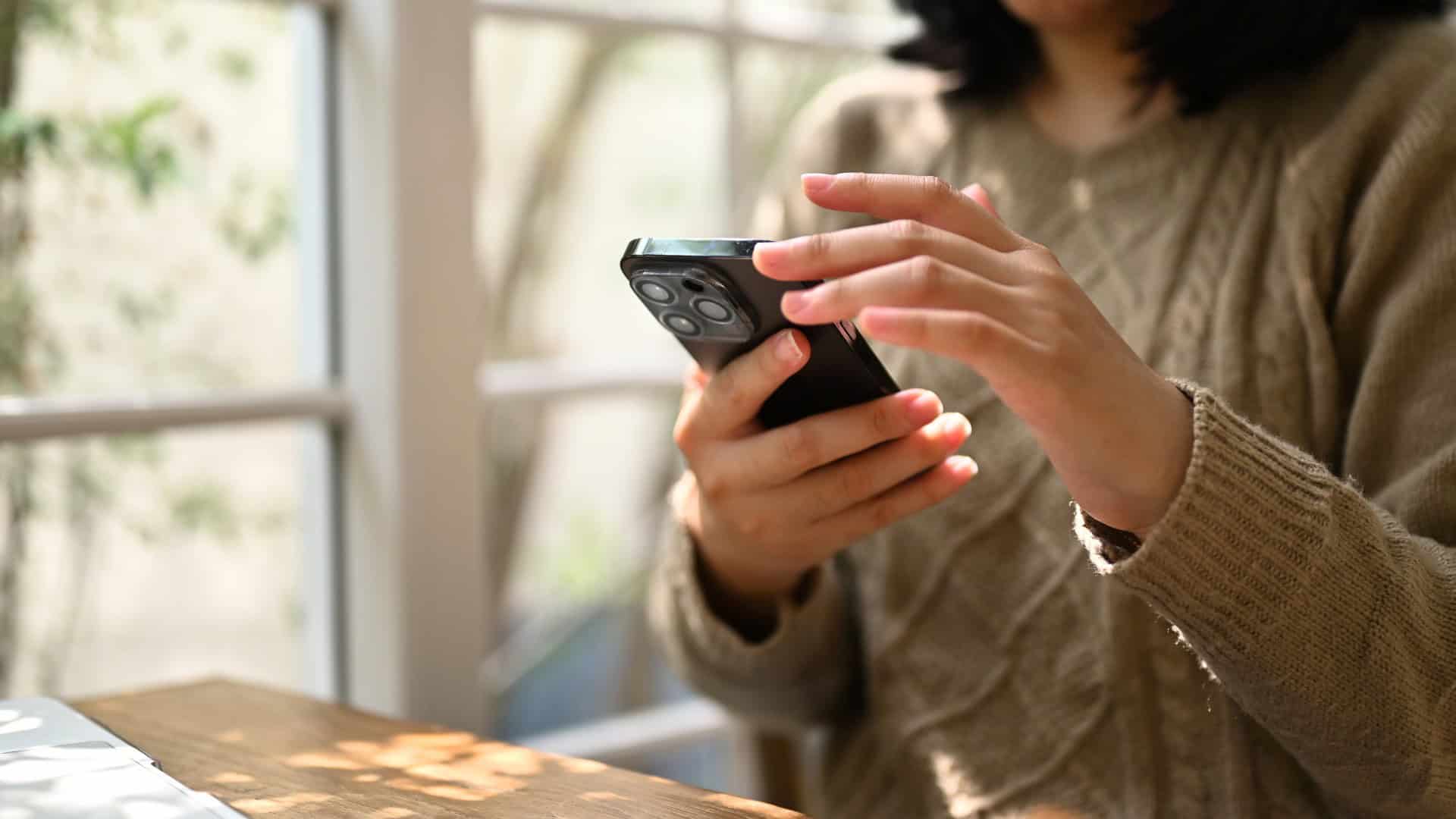 Person Using Smartphone for Communication Person holding smartphone, engaging in digital communication or browsing online.